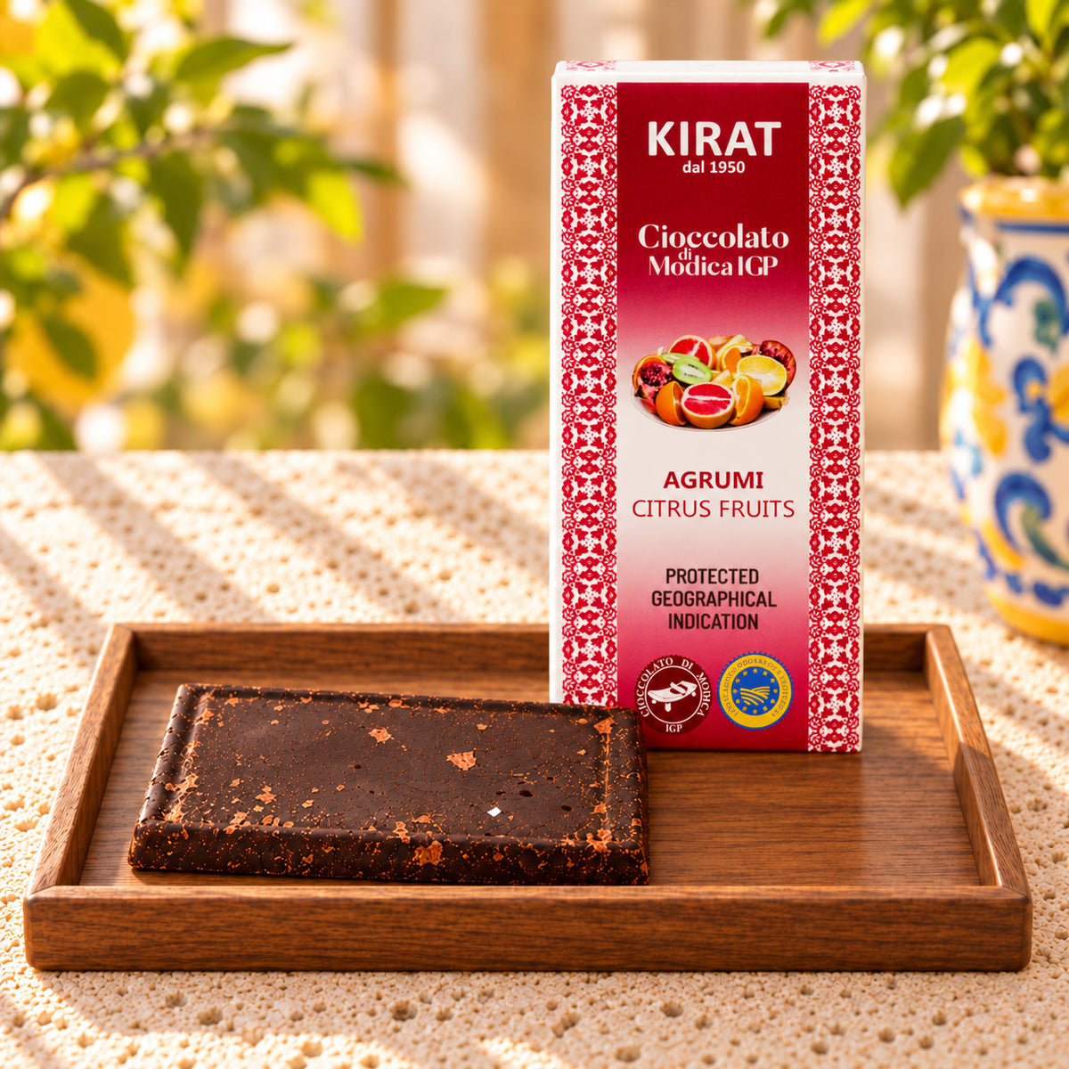 Cioccolato di Modica IGP Kirat agli agrumi, tavoletta coricata sul vassoio e confezione da 100 g in piedi