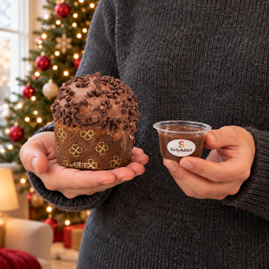 Panettoncino al cioccolato al latte tenuto in mano davanti alla tavola natalizia.
