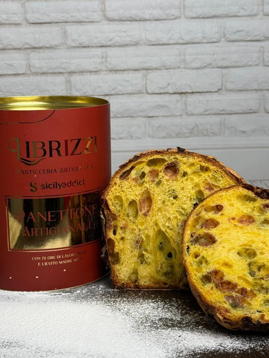 Panettone pistacchio e lamponi Librizzi Deluxe di SicilyAddict, tagliato con confezione davanti a una parete bianca